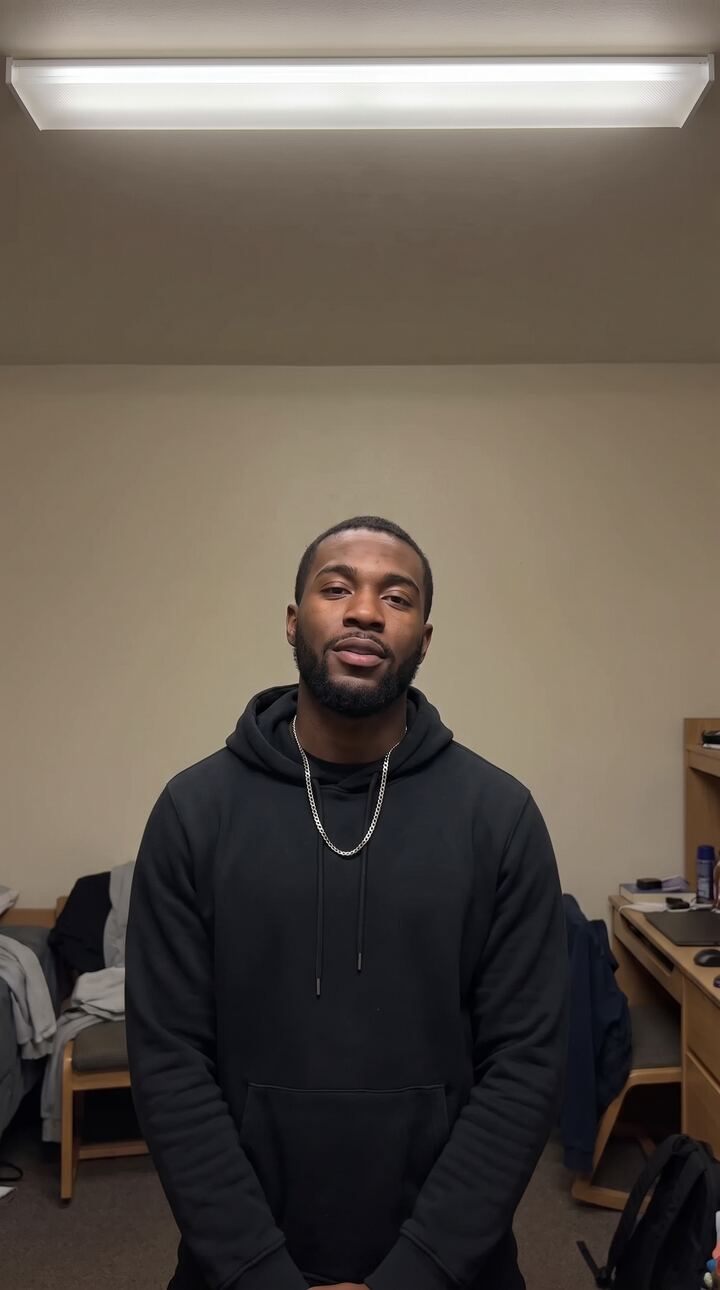 Creator standing in a plain bedroom with flat lighting